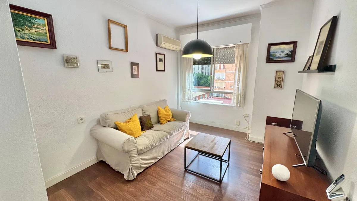 Separate sitting room with white sofa, television and street-facing window