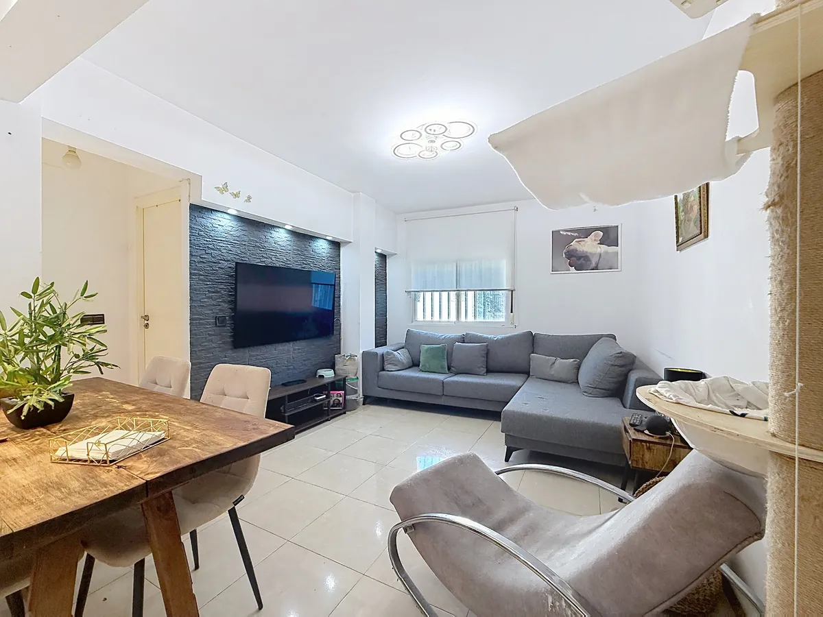 Bright living and dining room with grey corner sofa and armchair