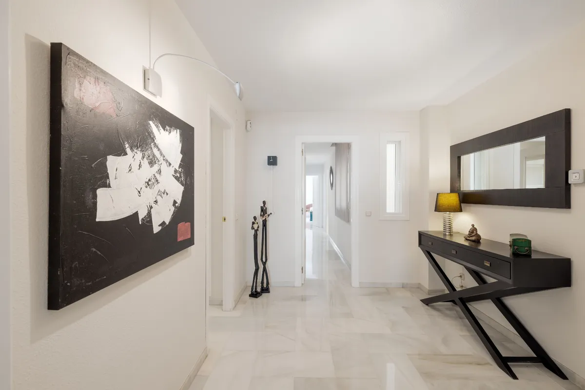 Long internal hallway connecting the apartment’s bedroom wing