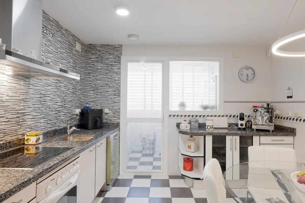 Long fitted kitchen with stainless-steel extractor and double sink