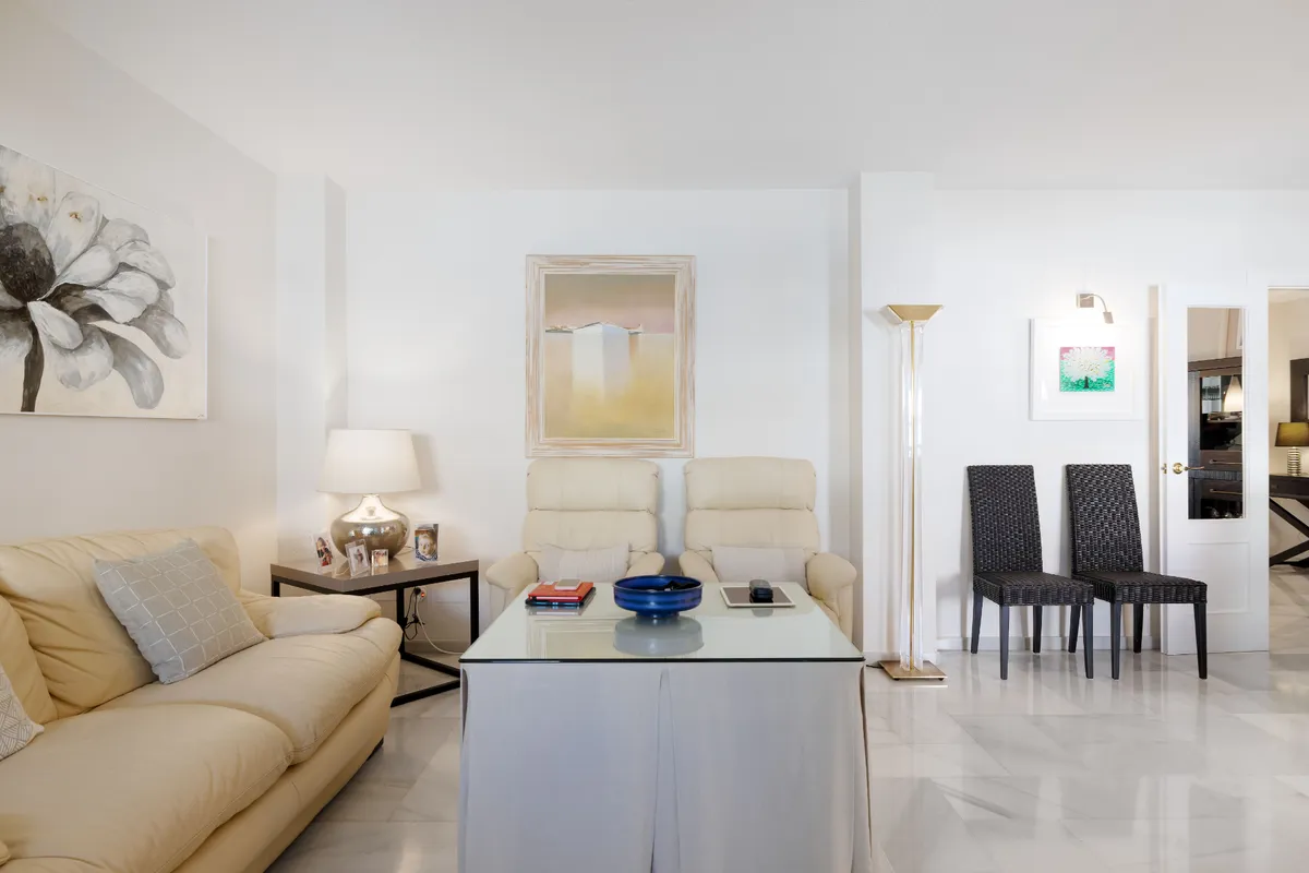 Elegant lounge with cream sofas, display shelves and floral artwork