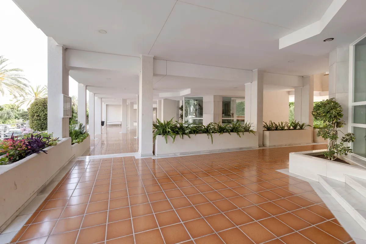 Covered communal terrace with terracotta floor and planted borders
