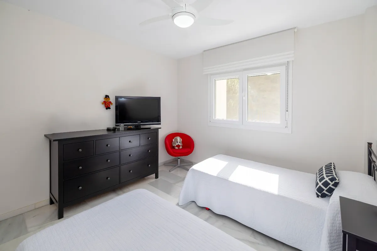 Double bedroom with yellow checked bedding and timber furniture