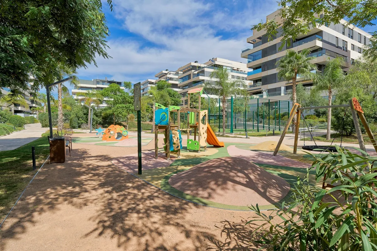 Communal children’s playground surrounded by trees and modern buildings