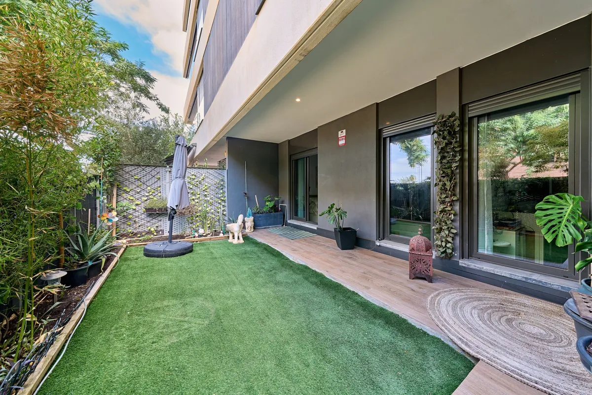 Large ground-floor garden terrace with artificial lawn and covered seating
