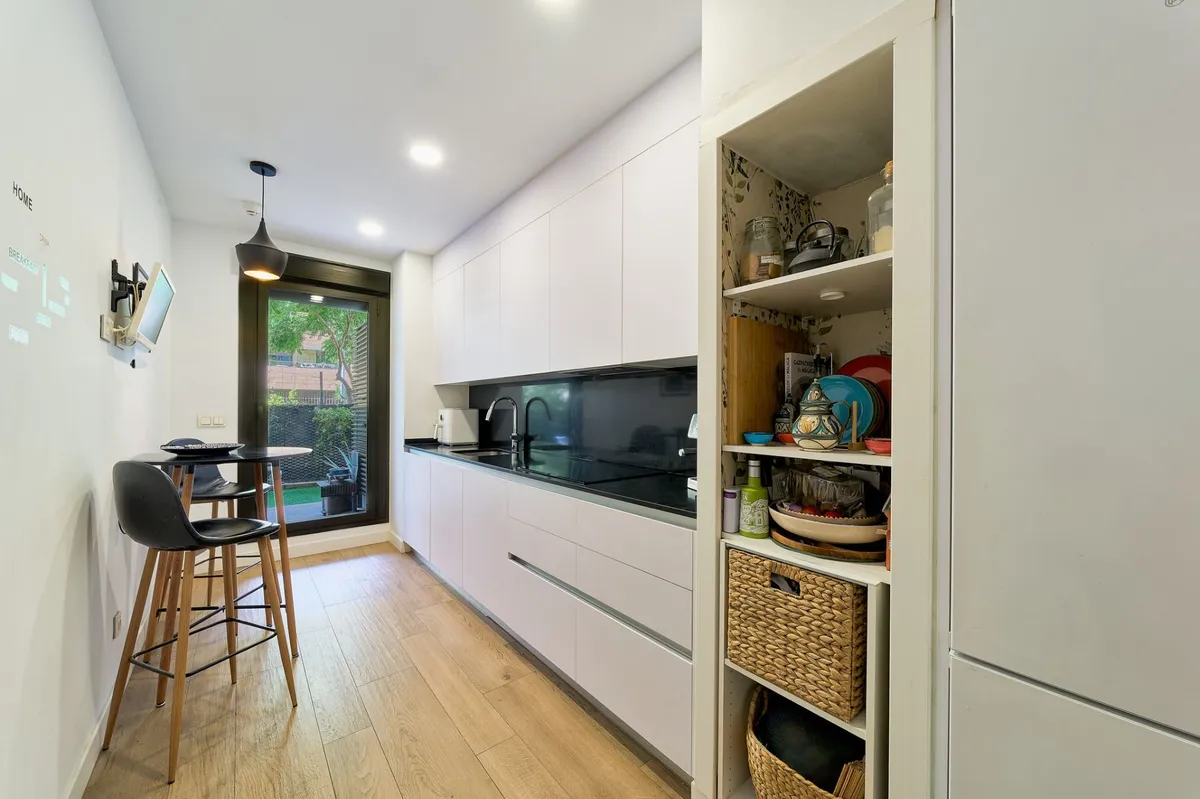 Modern white galley kitchen with breakfast bar and garden access