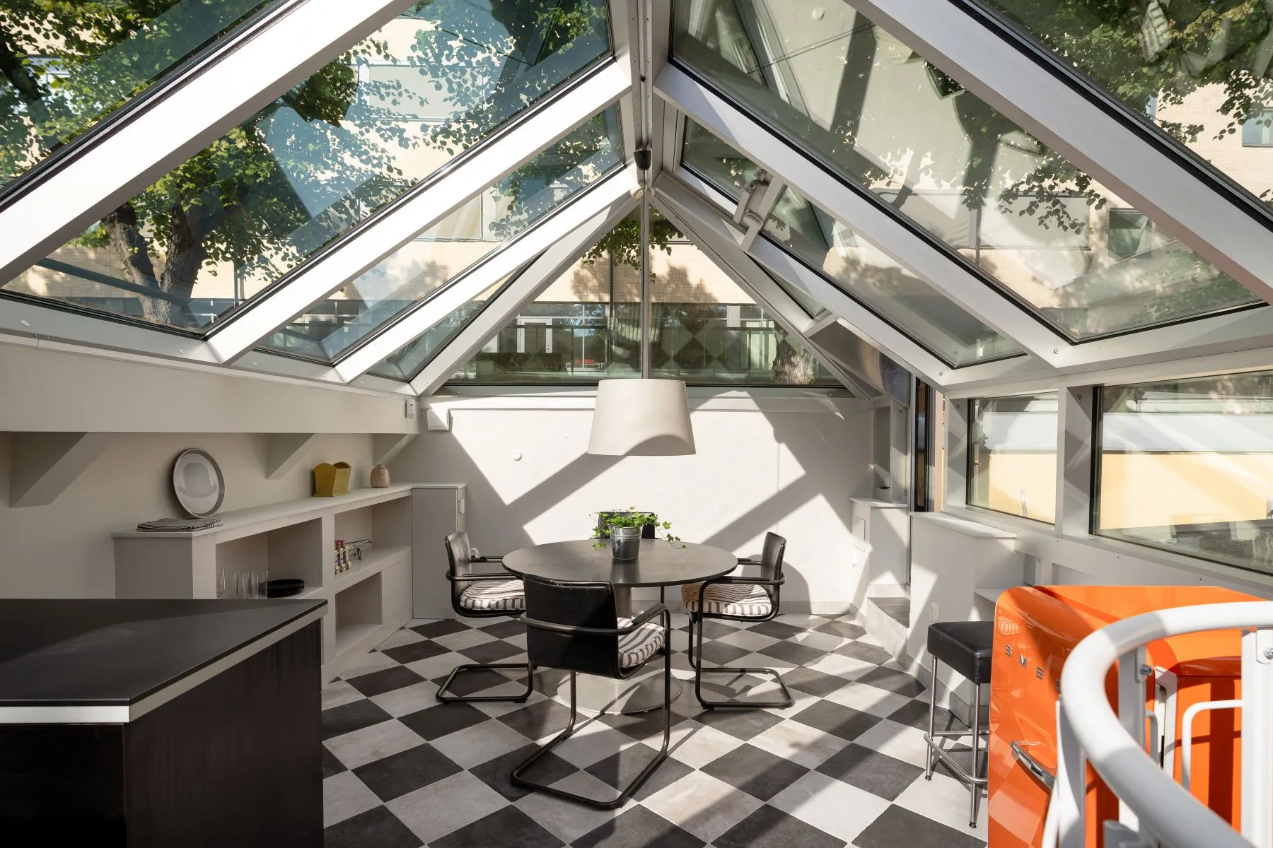 Private glazed conservatory with dining table and monochrome tiled floor