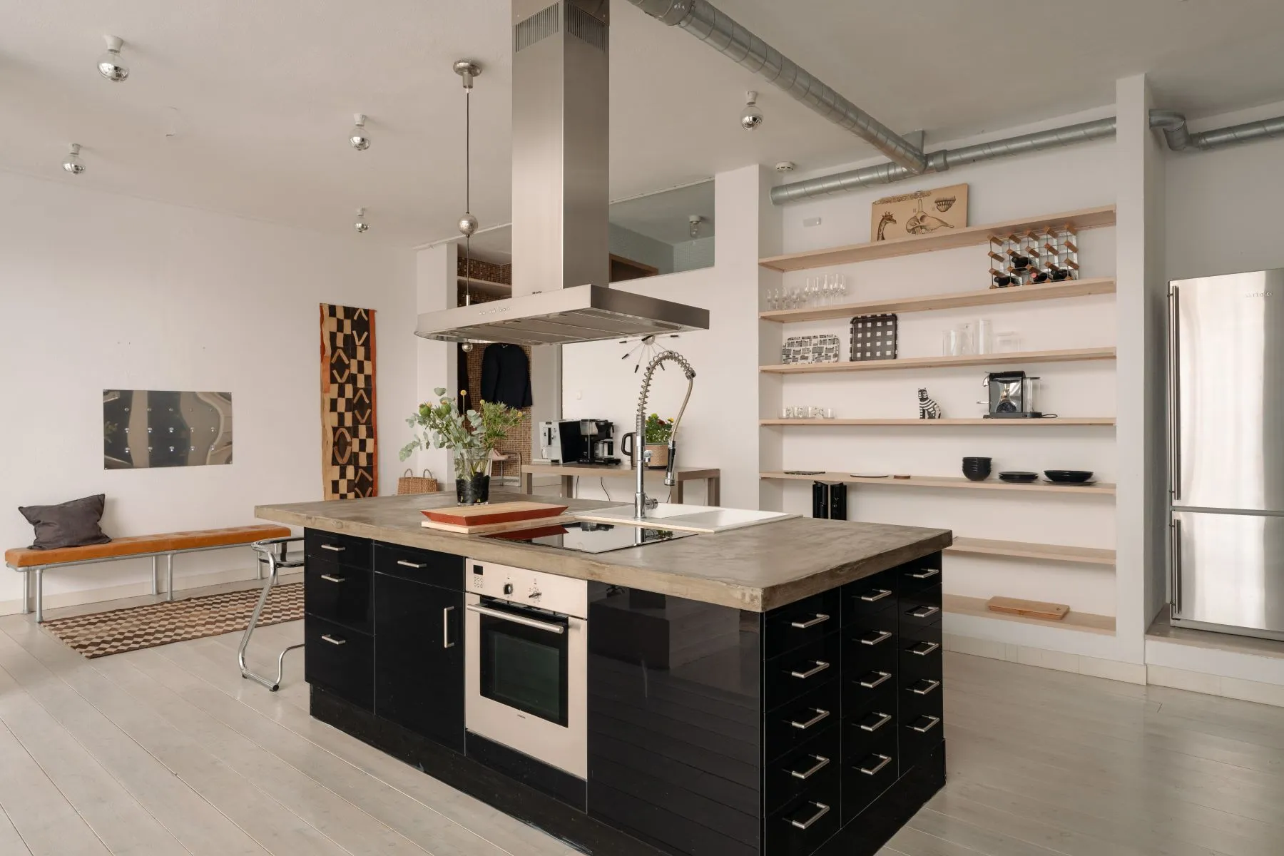 Large dark kitchen island with integrated cooking and extensive open shelving