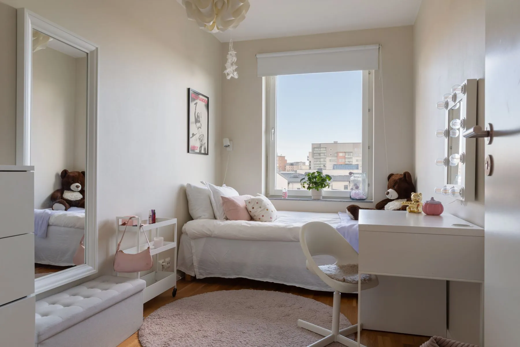 Bright family bedroom with white furniture and large city-facing window