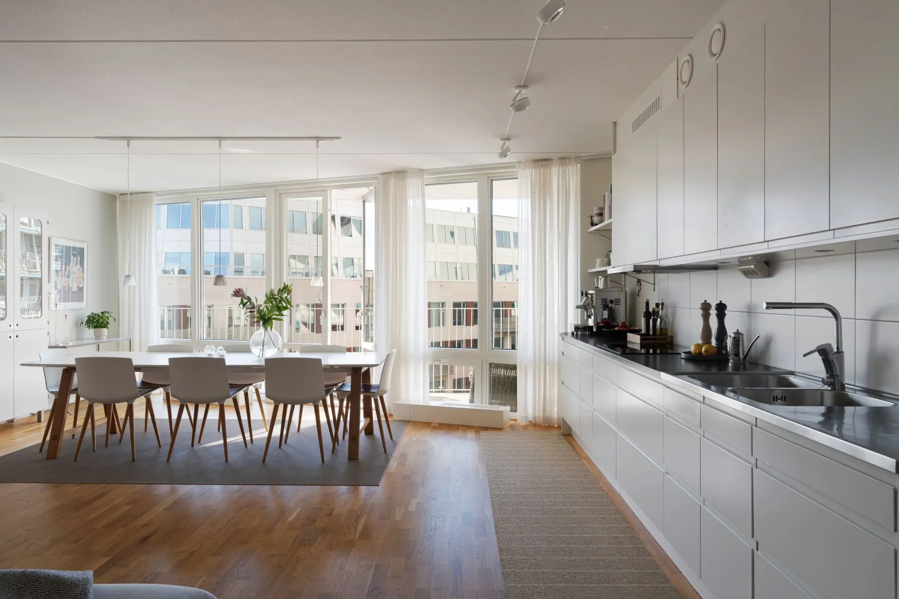 Open-plan white kitchen and dining area filled with natural Stockholm light