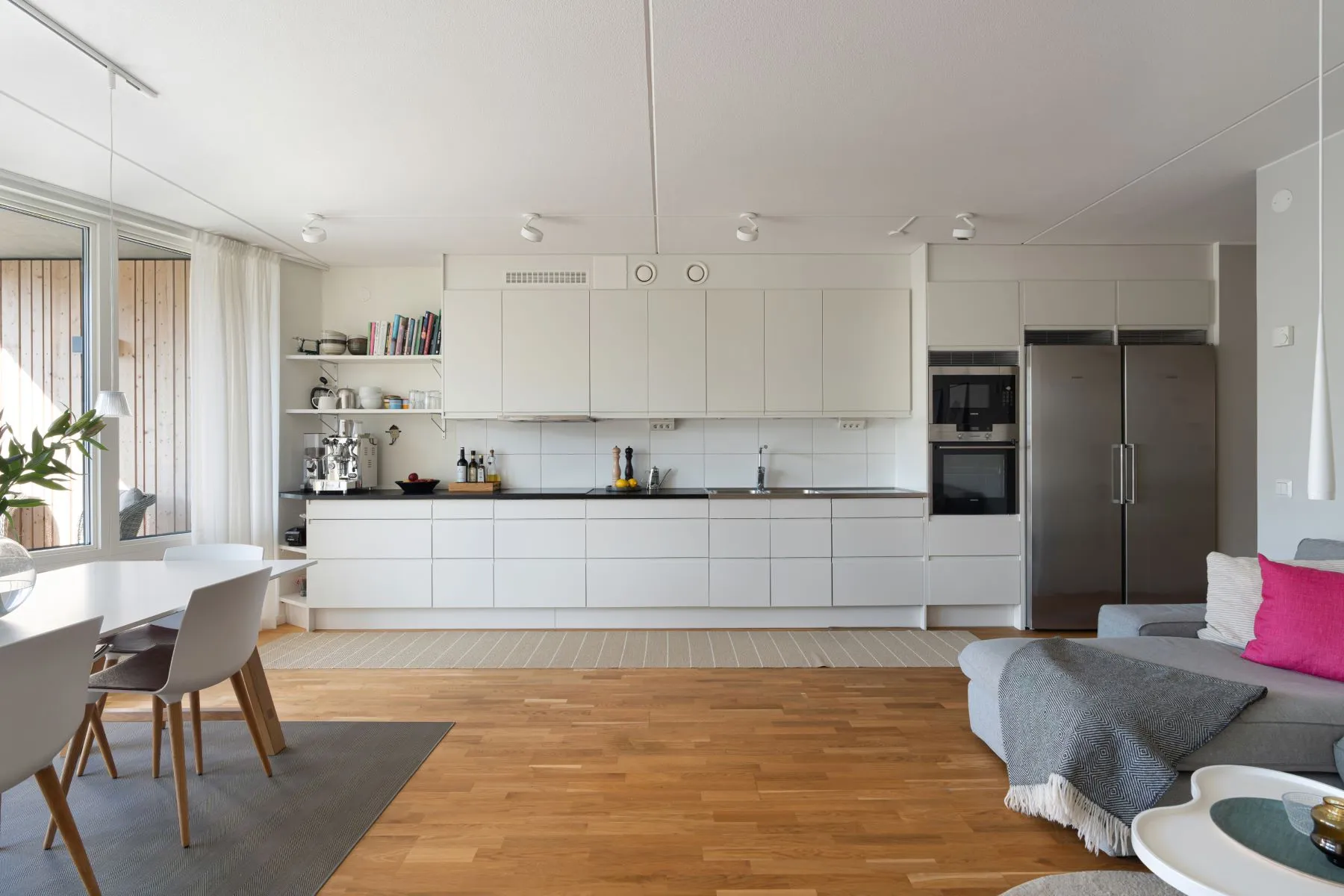 Streamlined white fitted kitchen with extensive cabinetry and integrated appliances