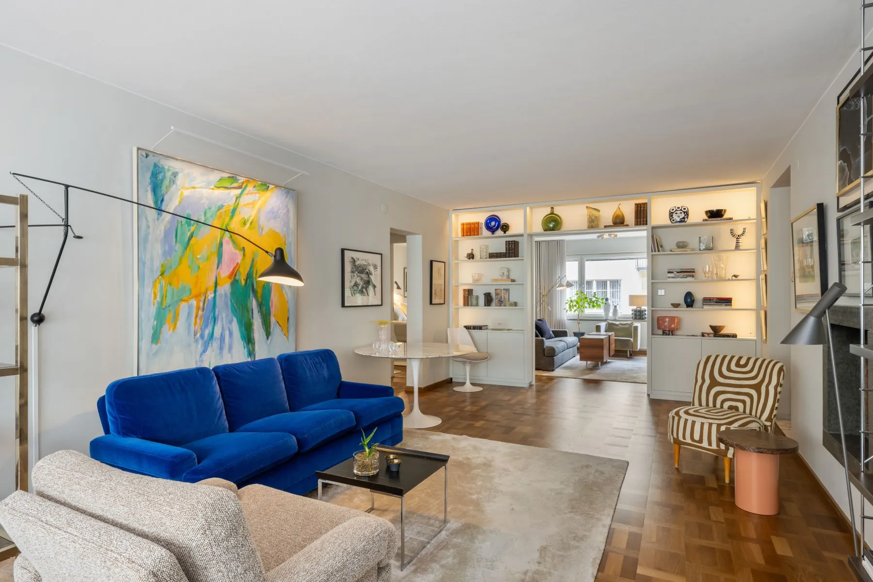 Main lounge with vivid blue sofa, original art and opening to the TV room
