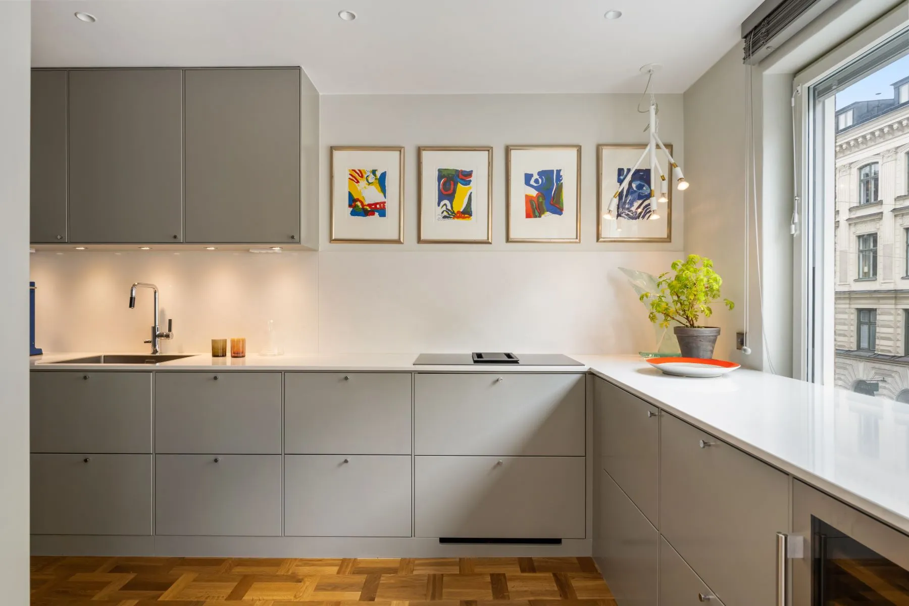 Grey U-shaped kitchen with induction hob and colourful framed artwork