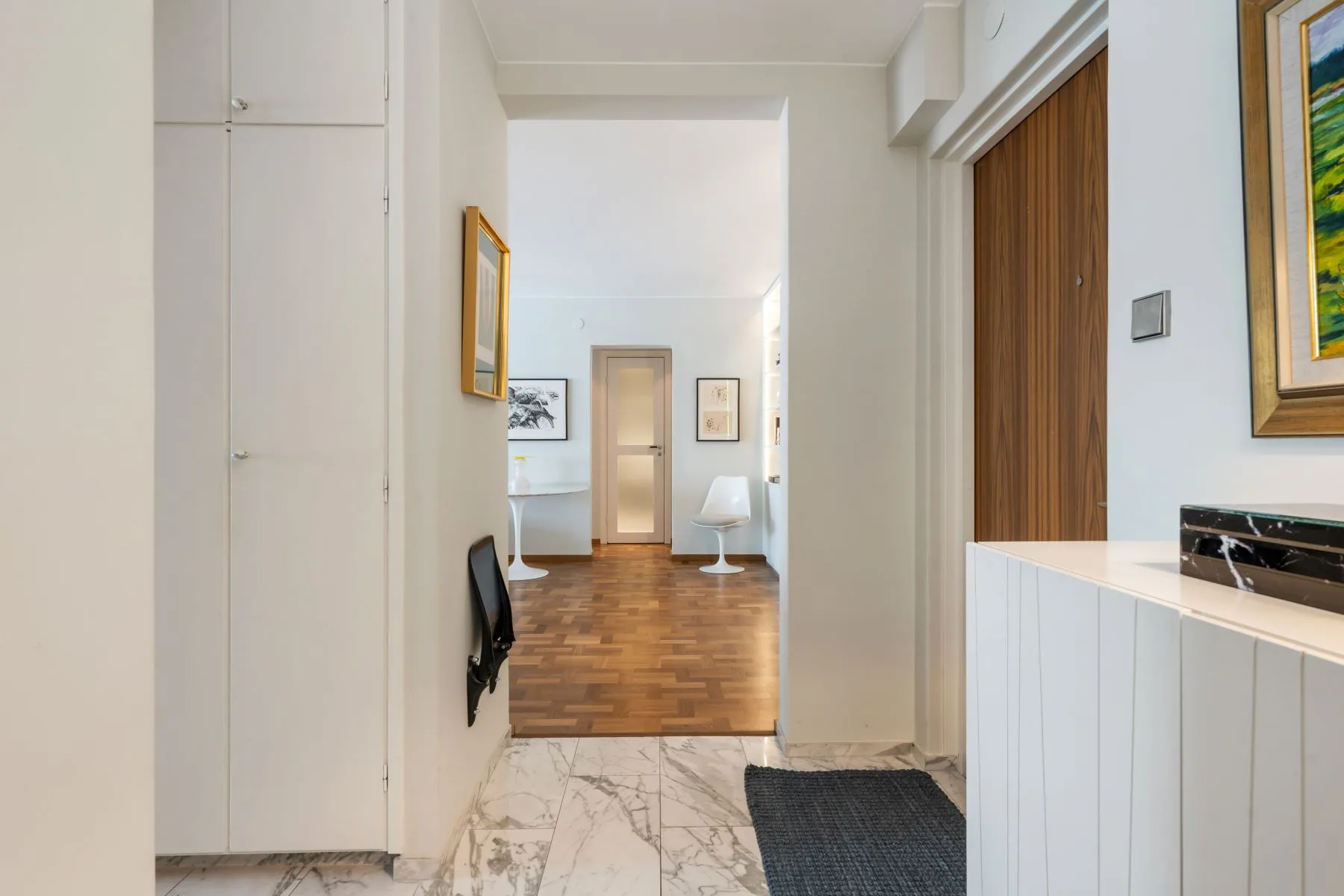 Apartment hallway with oak parquet and bright reception rooms beyond