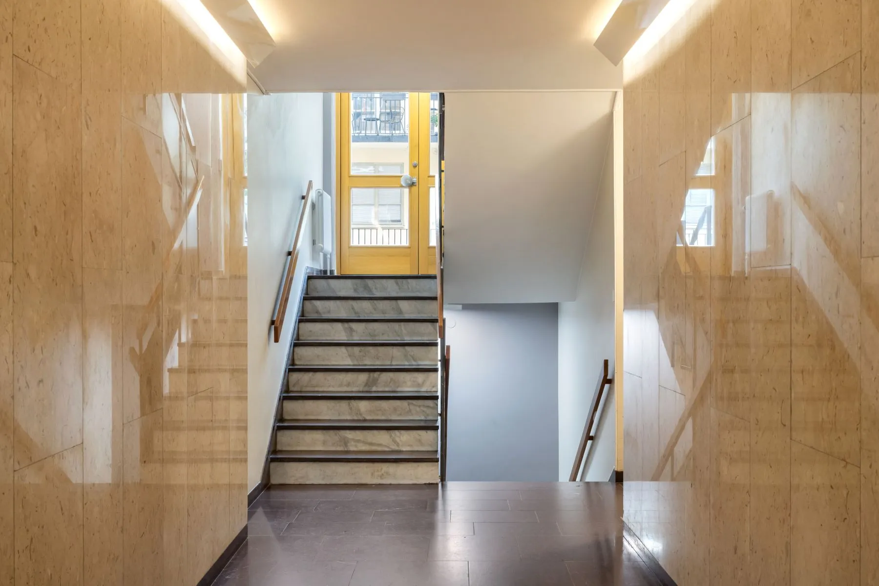 Polished stone residential staircase with daylight from the street entrance