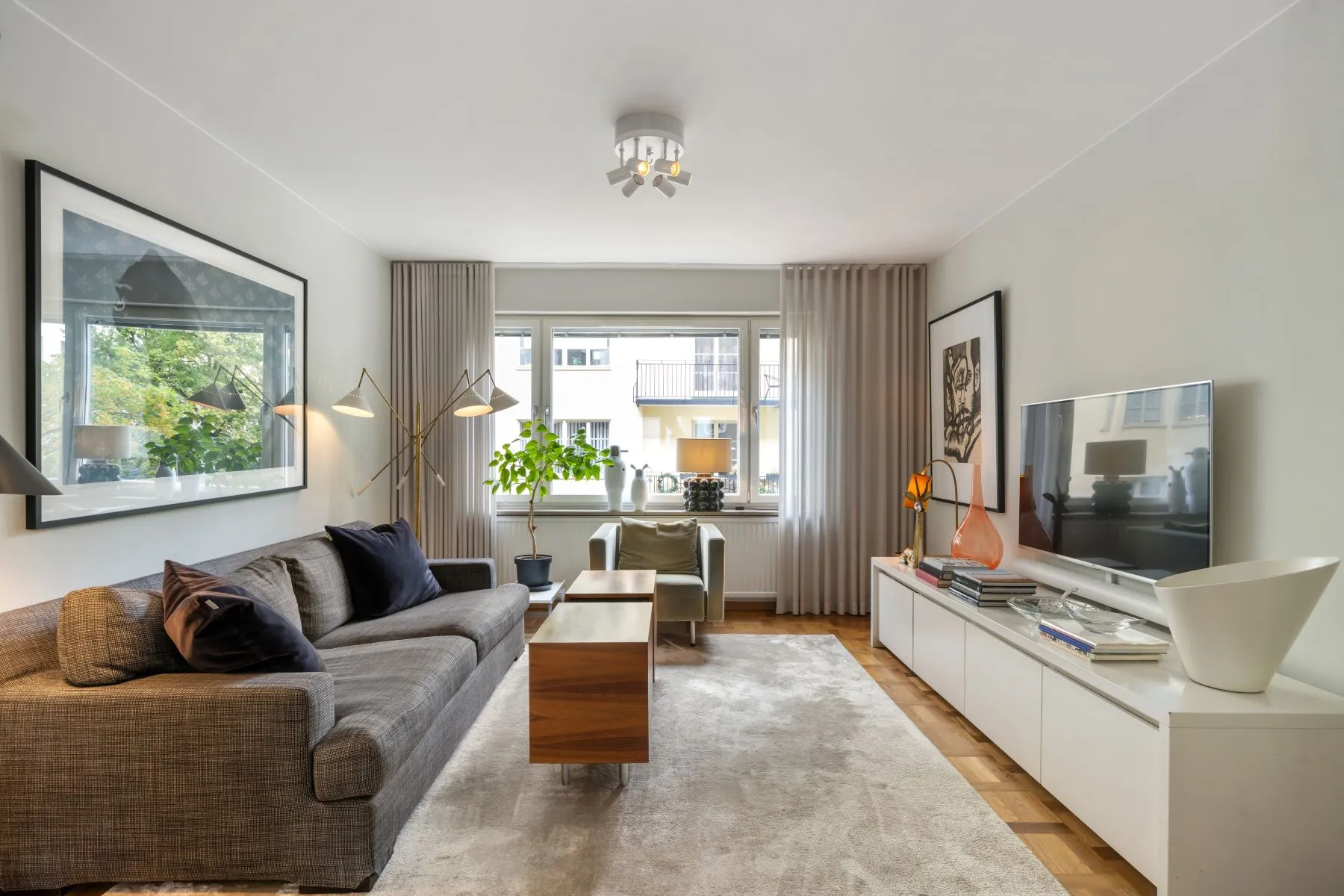 Separate courtyard-facing TV lounge with sofa and contemporary media storage