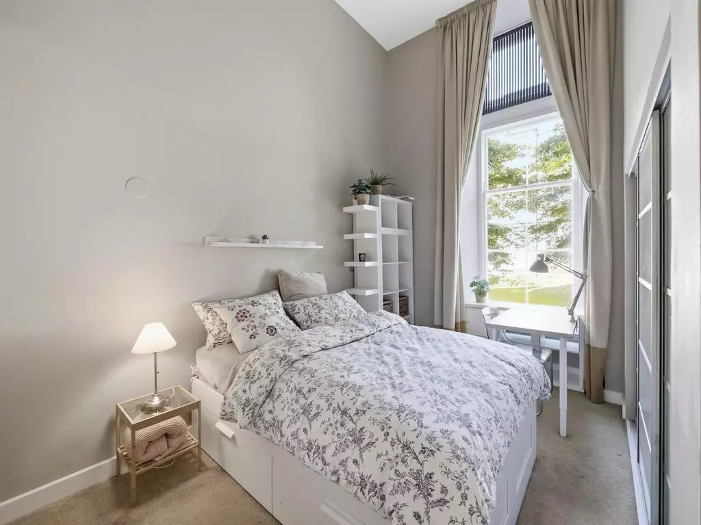Second double bedroom with tall windows and leafy views