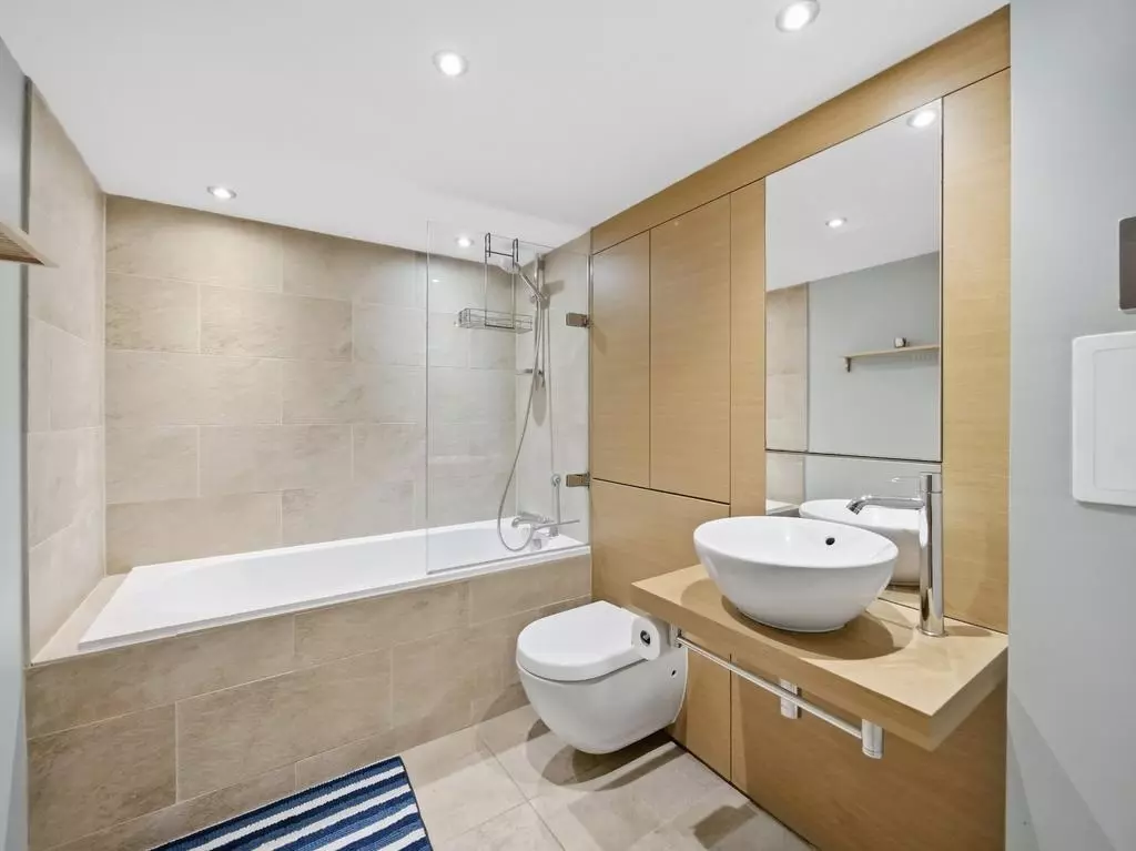 Modern bathroom with shower over bathtub and fitted vanity