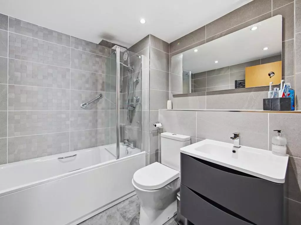 Modern bathroom with bathtub, overhead shower and vanity storage