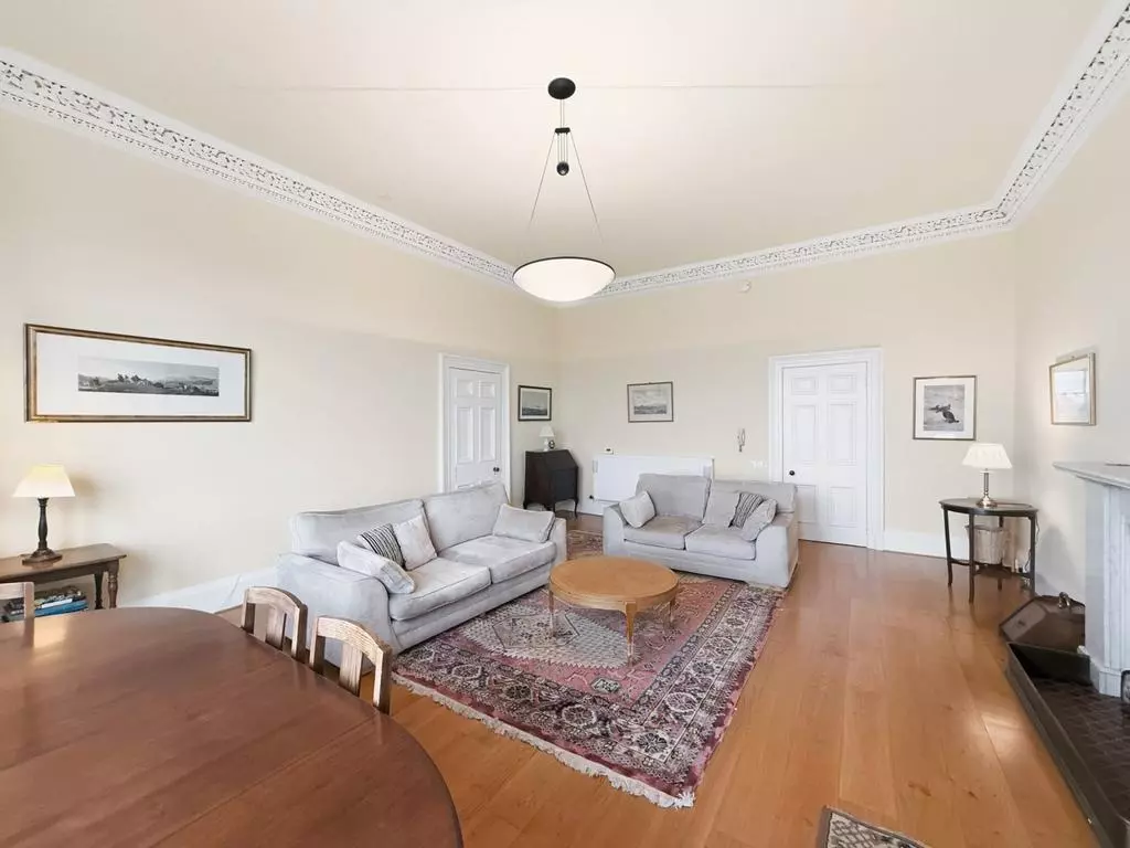 Spacious sitting room with sofas, wooden floor and period details
