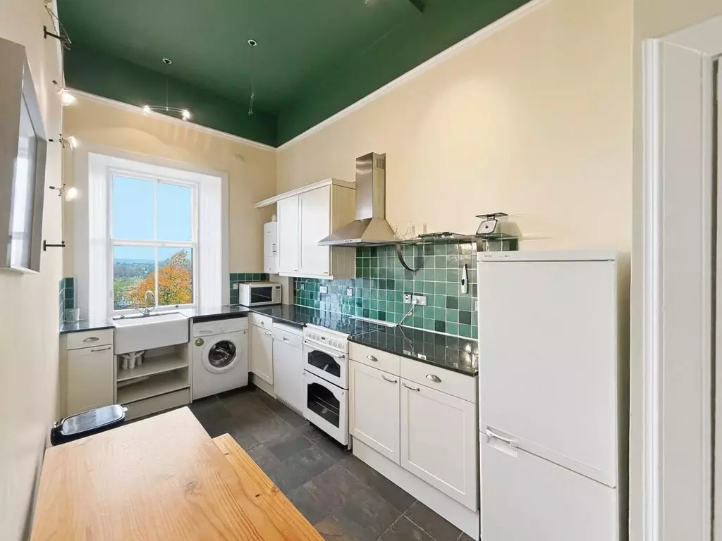Fitted kitchen with Belfast sink and green tiled splashback
