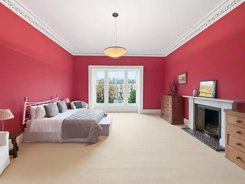 Generous double bedroom with decorative fireplace and bay window
