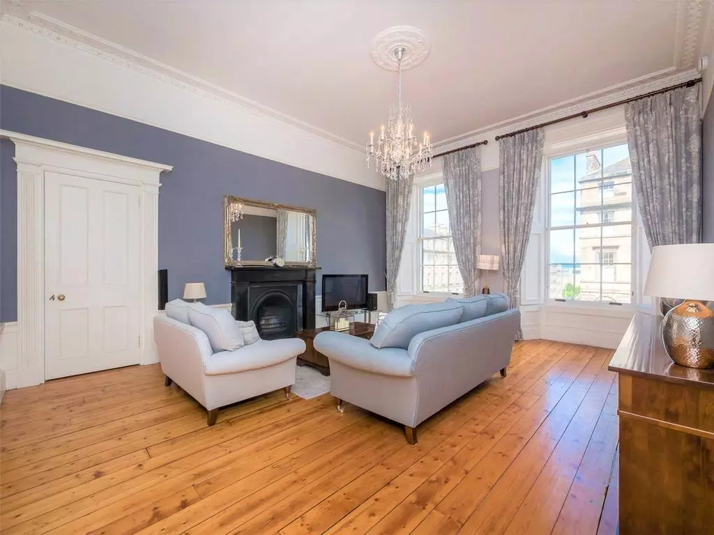 Bright living room seating arranged around the traditional fireplace