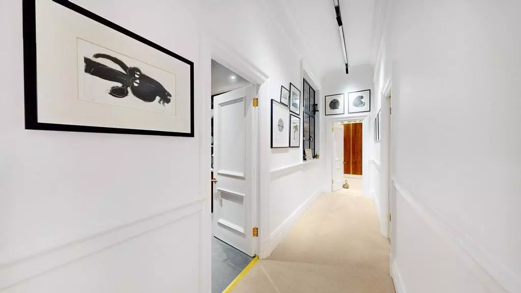 Gallery-style entrance hallway with monochrome artwork and panelled walls